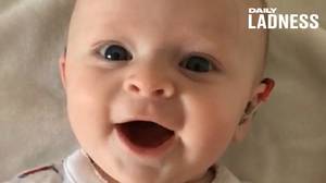 当爸爸转动她的助听器时，心灵录像显示婴儿微笑