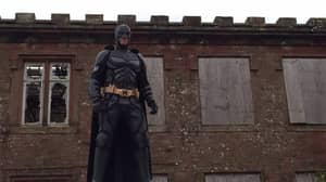 小伙子穿着蝙蝠侠的衣服正在保护孩子免受这种“小丑狂热”的侵害