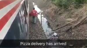 小伙子送货司机将披萨带到被困在停滞火车上的饥饿的乘客