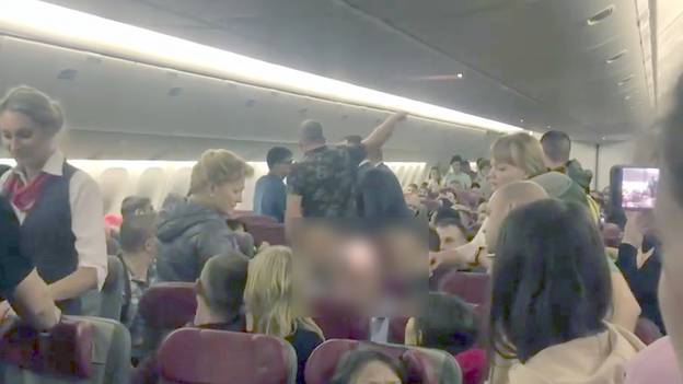 醉酒男子试图打开机舱门，乘客用保鲜膜将其包裹起来