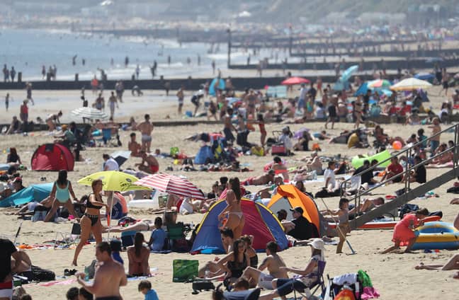 人们蜂拥而至，在多塞特郡的伯恩茅斯海滩享受良好的天气。信用：PA