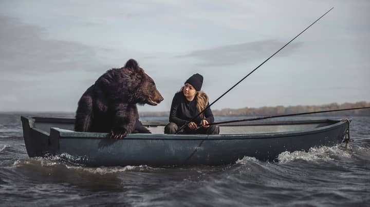 女人用救出的棕熊在船上钓鱼