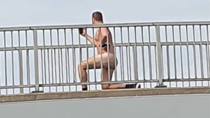 裸体男子在繁忙的道路上发现蹲在桥上