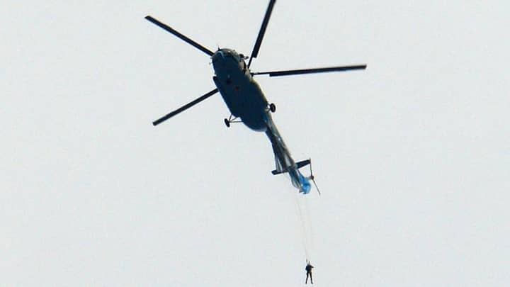 慢胎陷入困境后，跳伞运动员从直升机悬挂着“width=