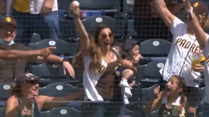 妈妈抱着孩子在棒球比赛中用一只手接球，真是不可思议