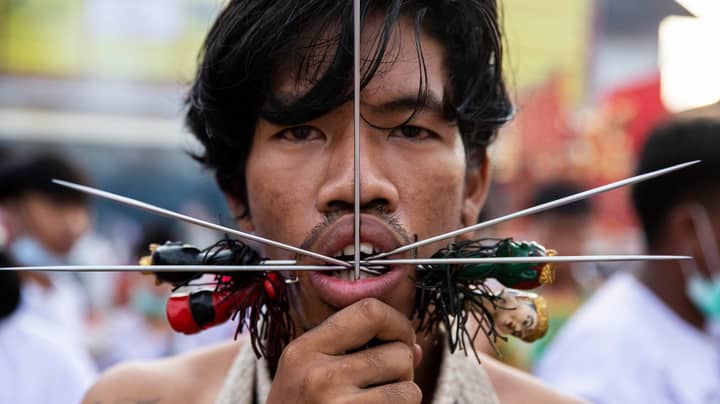 在泰国素食节上，礼拜者用金属钉和斧头刺穿面部