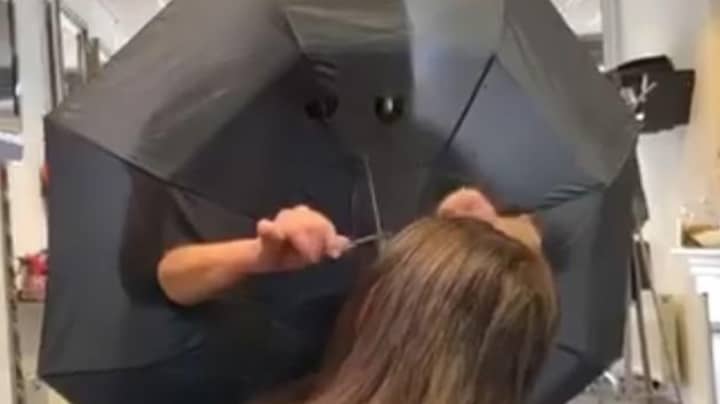 美发师在伞中切割孔，以在客户之间产生障碍